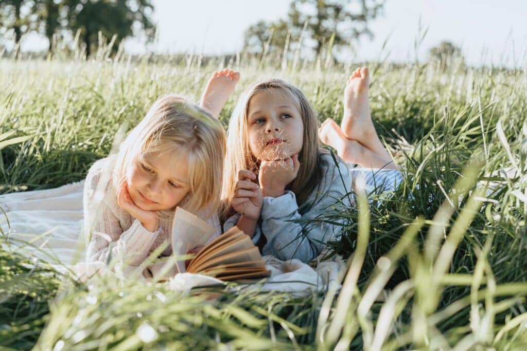 Two girls reading in the grass during summer time
